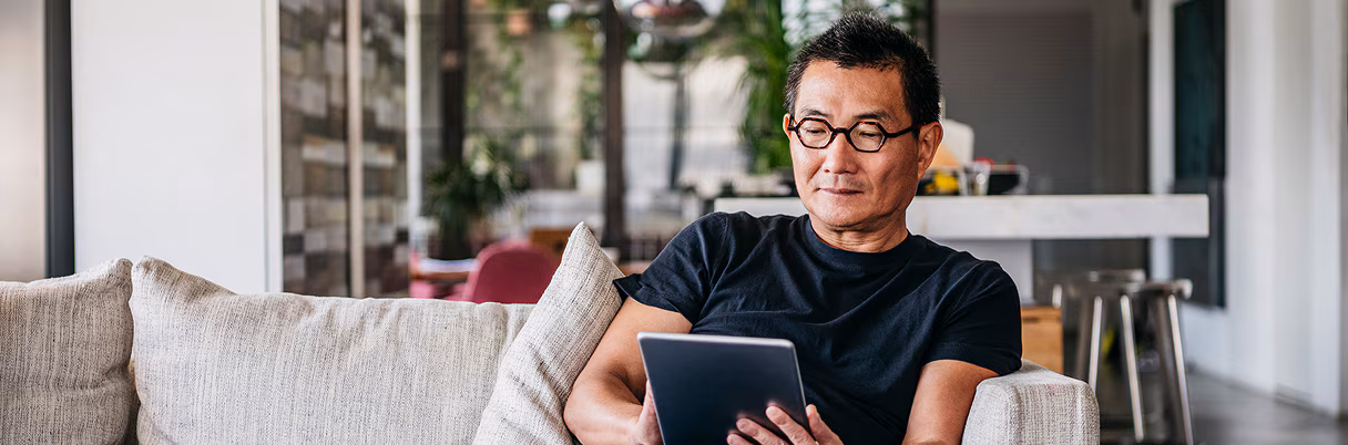 An investor looks at his tablet while seated on his couch